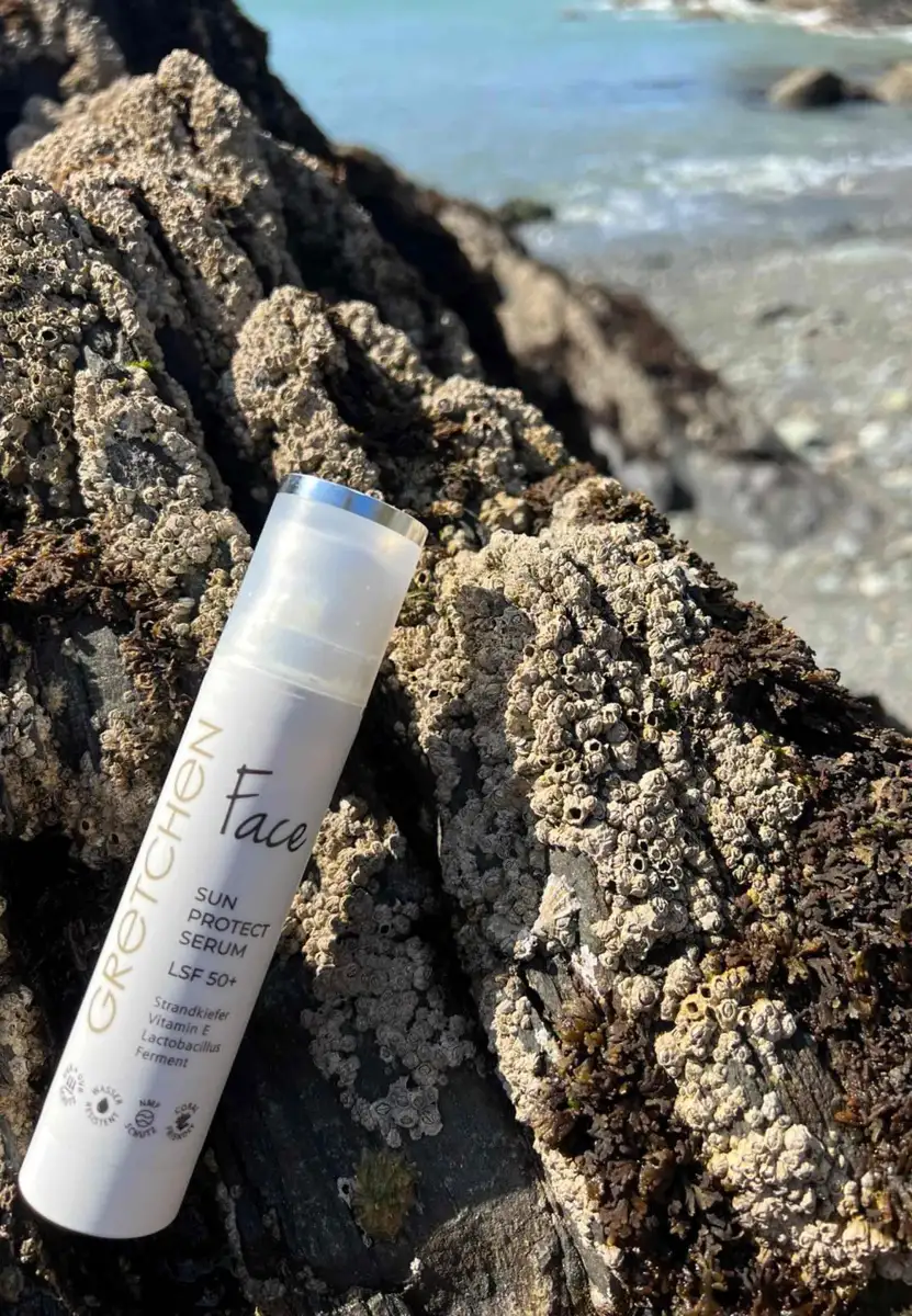 Gretchen Face Sun Protect Serum SPF 50+ on a sunlit rock by the sea – daily UV protection